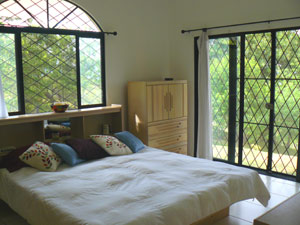 The bedroom in the master suite is a large space with handsome large curving window and sliding glass doors. 