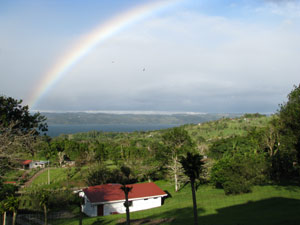 A rainbow frames the view of the lake from the home. The cabina is seen at the bottom of the frame. 